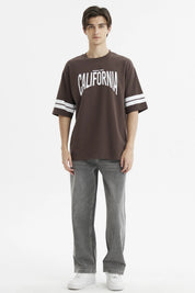 Polera oversize chocolate con estampado frontal California en blanco y rayas en las mangas estilo casual relajado