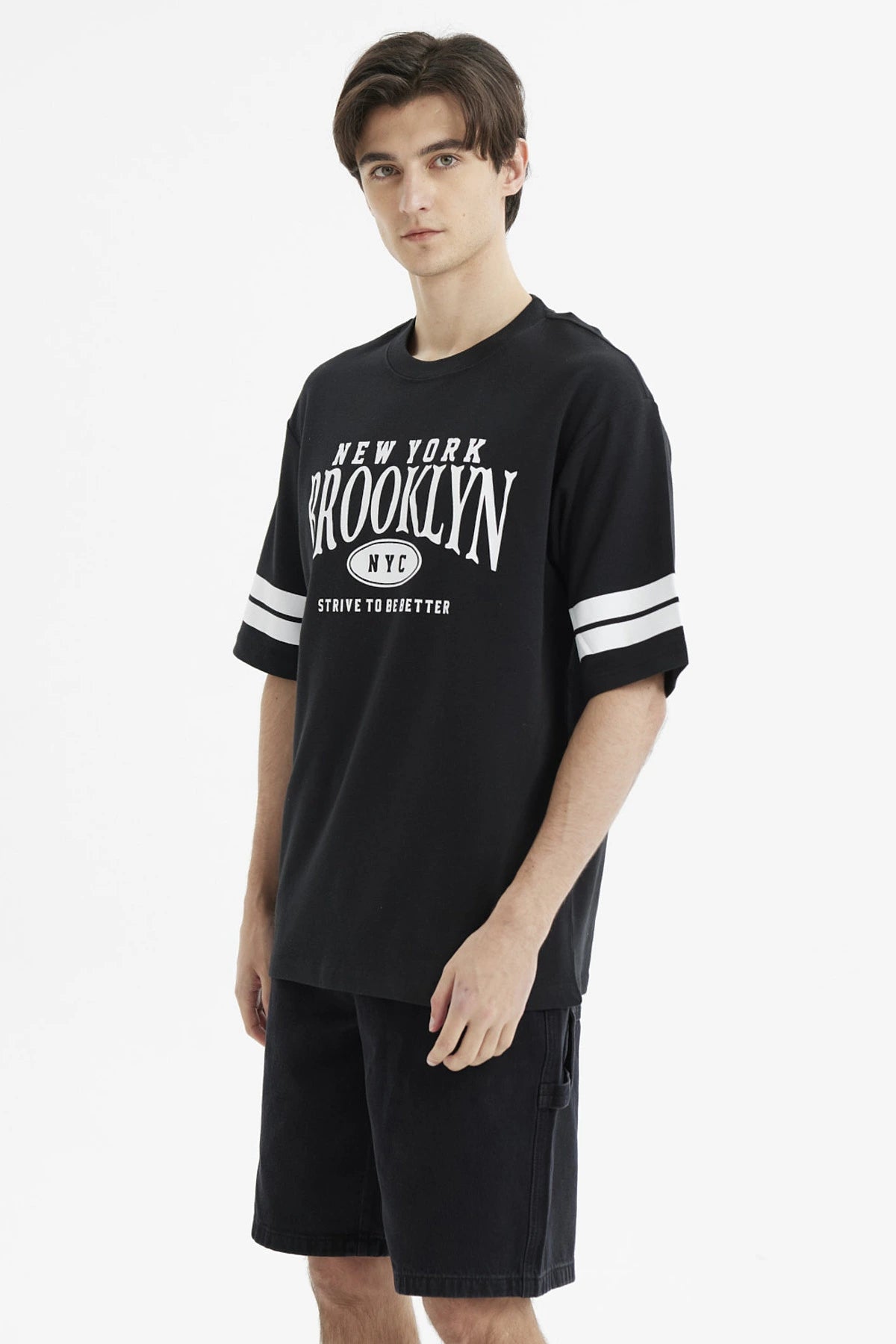 Polera oversize negra con estampado frontal New York Brooklyn y texto Strive to be better estilo urbano casual