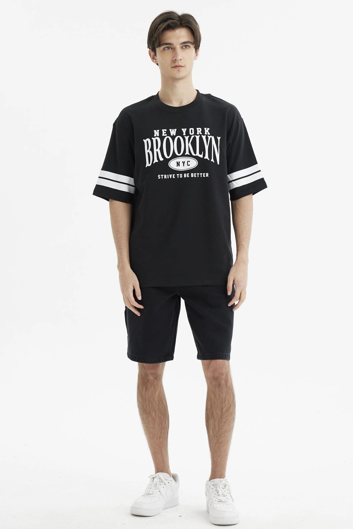 Polera oversize negra con estampado frontal New York Brooklyn y texto Strive to be better estilo urbano casual