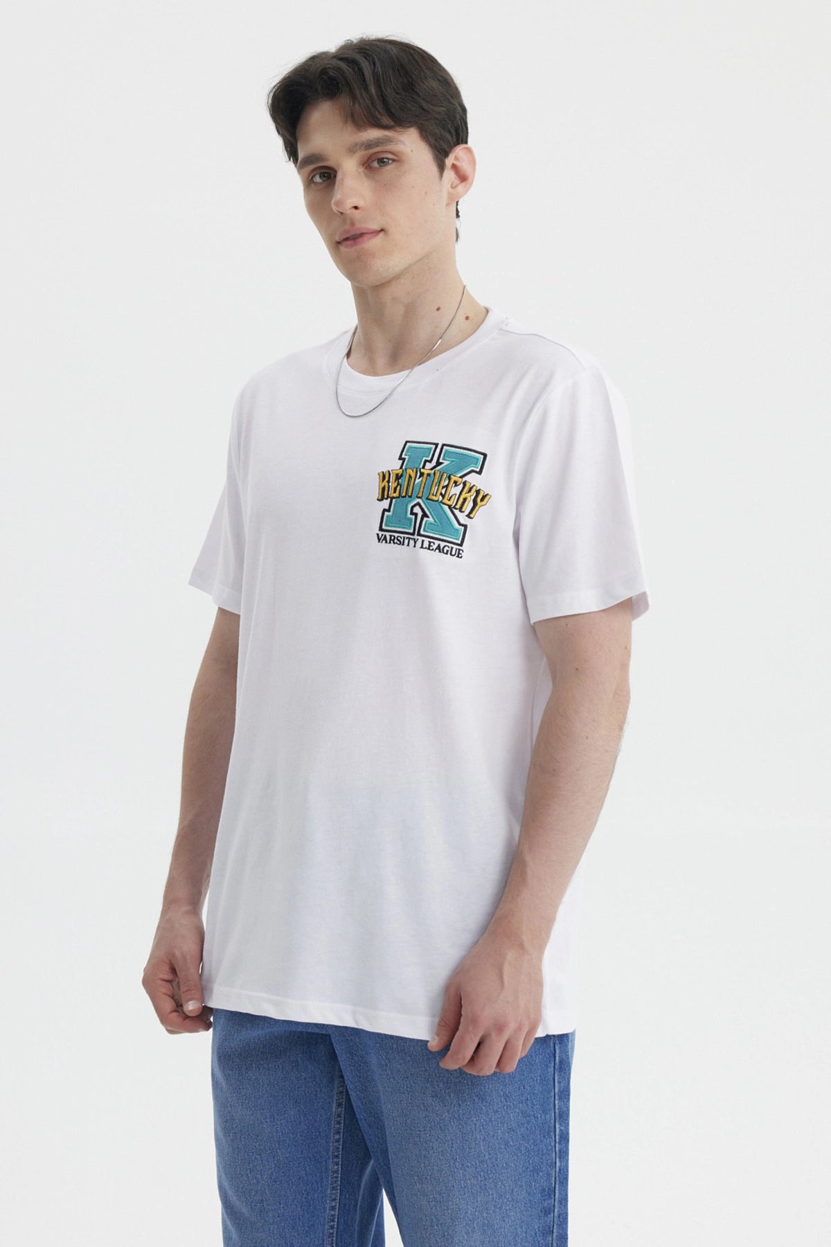 Polera oversize blanca con bordado colorido en el pecho estilo varsity que dice Kentucky con letra grande y audaz