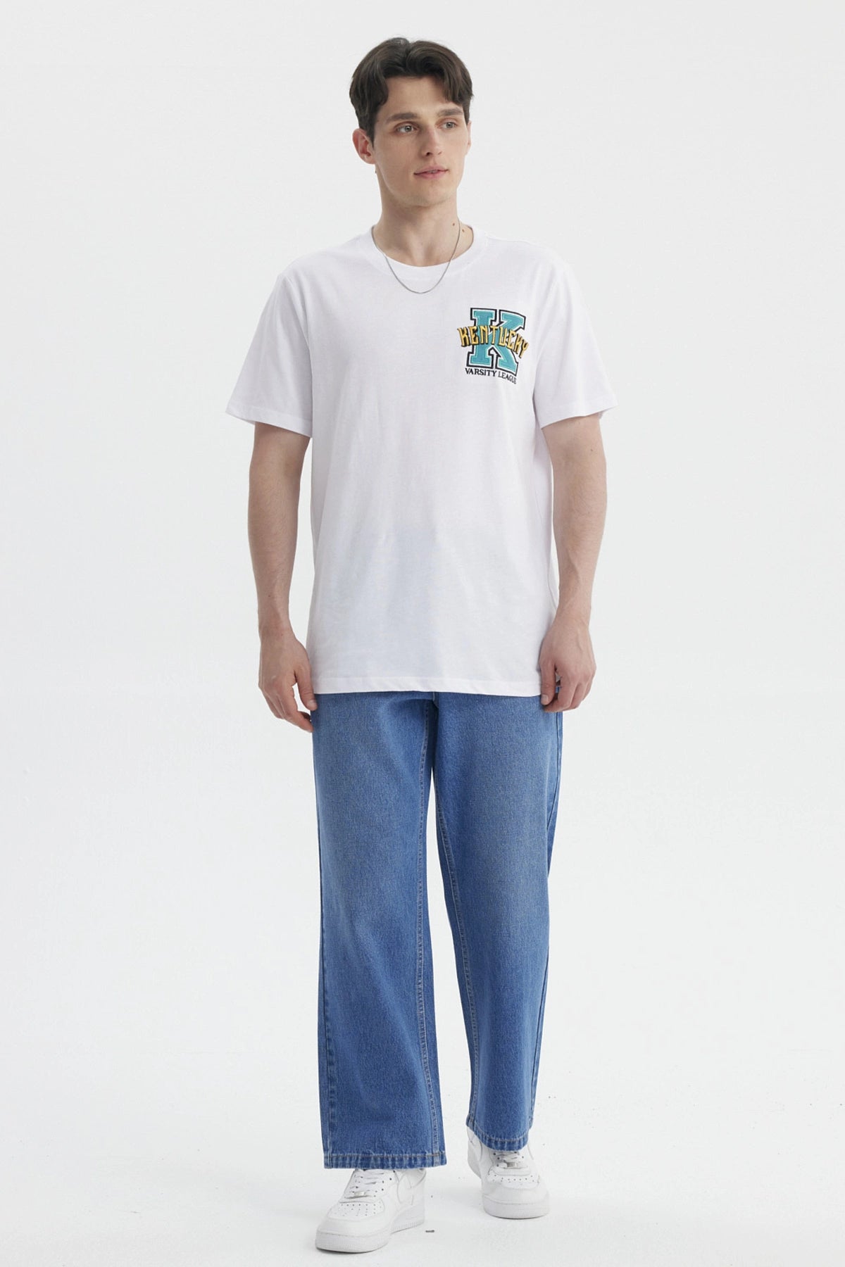 Polera oversize blanca con bordado colorido en el pecho estilo varsity que dice Kentucky con letra grande y audaz