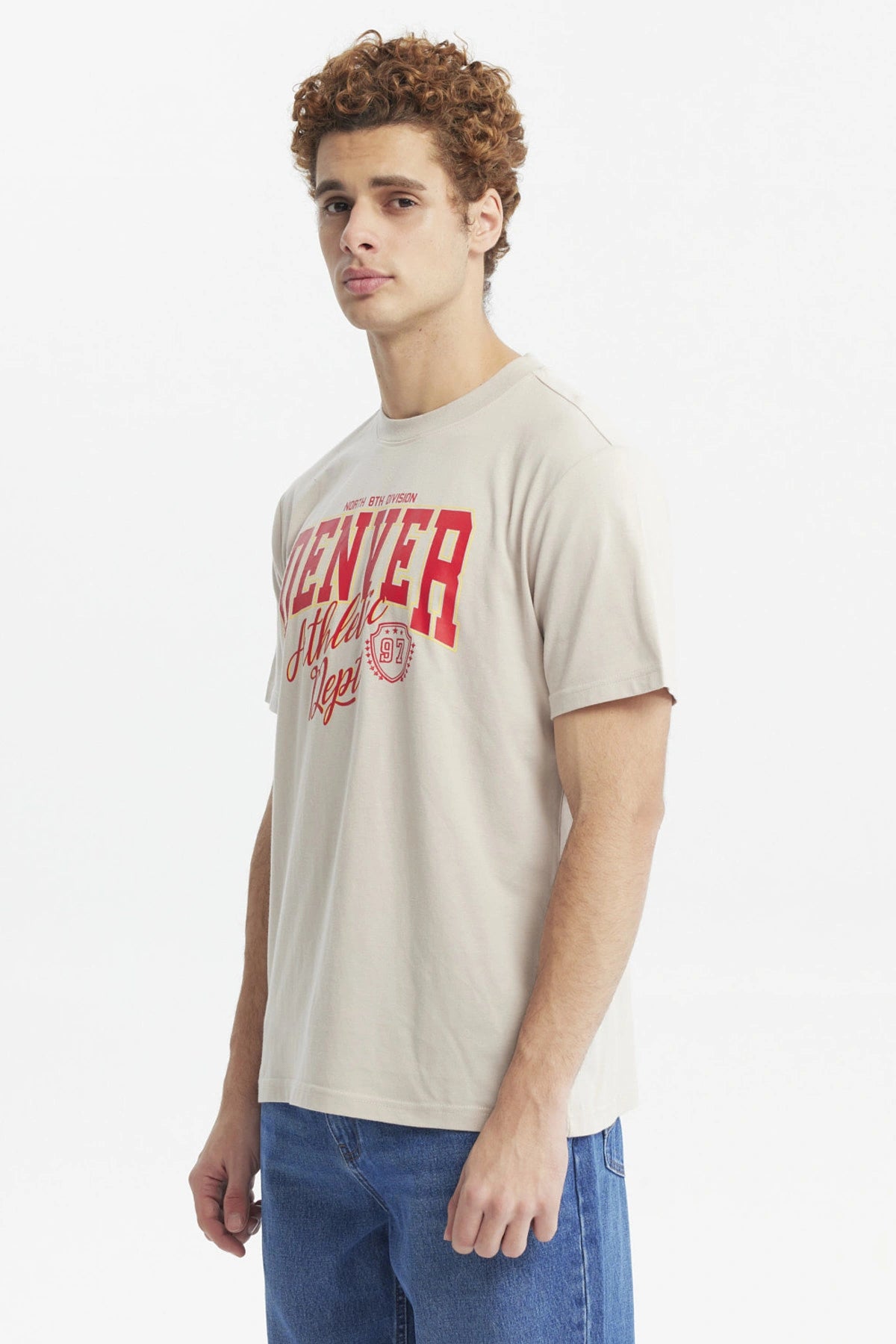 Polera oversize beige con texto rojo "Denver Athletic Dept" al frente estilo casual urbano