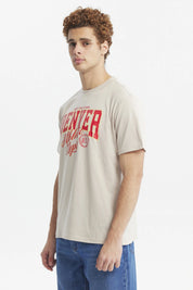 Polera oversize beige con texto rojo "Denver Athletic Dept" al frente estilo casual urbano