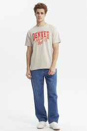 Polera oversize beige con texto rojo "Denver Athletic Dept" al frente estilo casual urbano