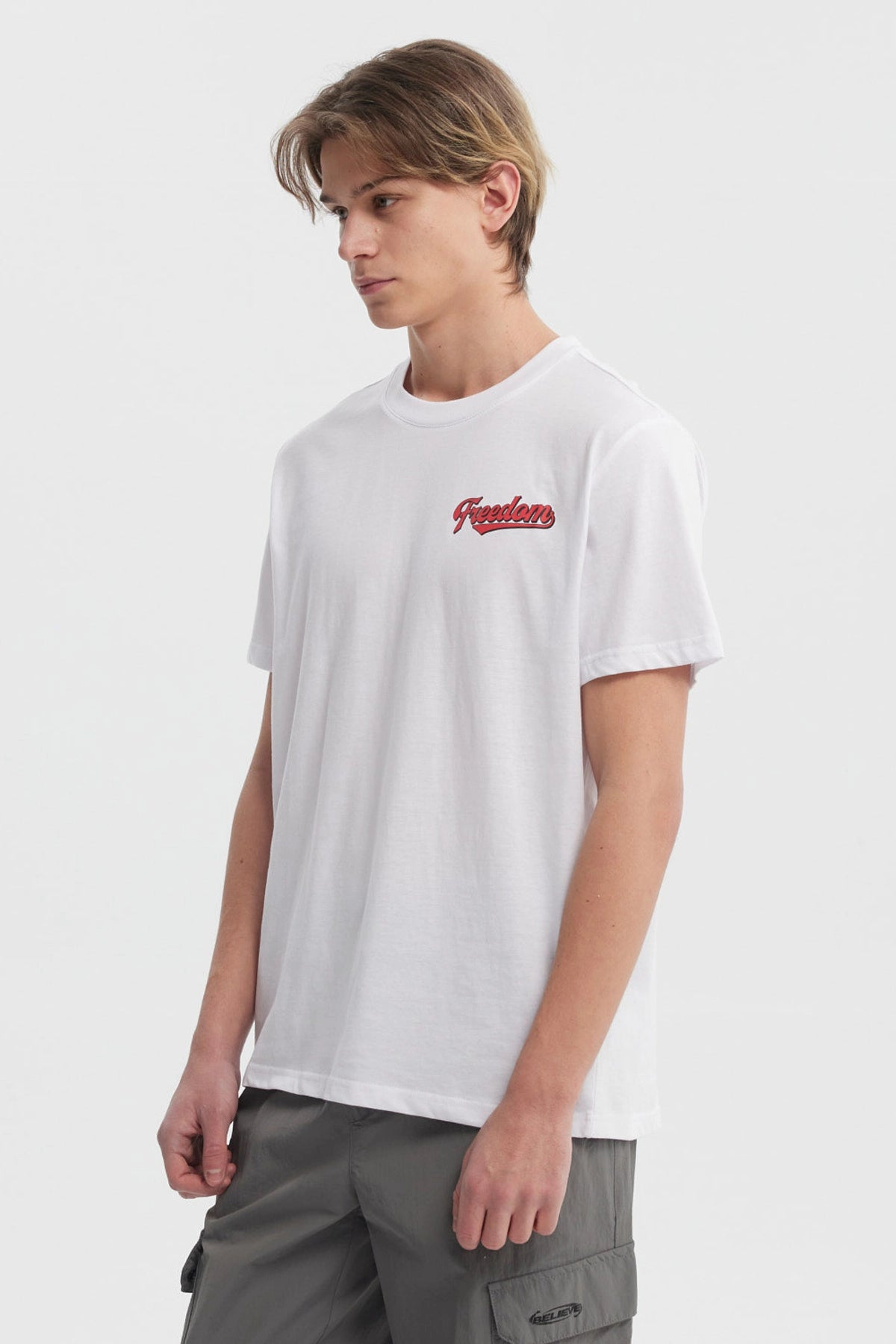 Polera blanca hombre regular fit con texto Freedom en rojo en el pecho diseño simple y moderno sin estampas traseras
