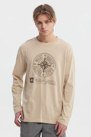 Polera beige oscuro hombre con brújula grande central y texto en el frente estilo casual relajado sin estampa trasera