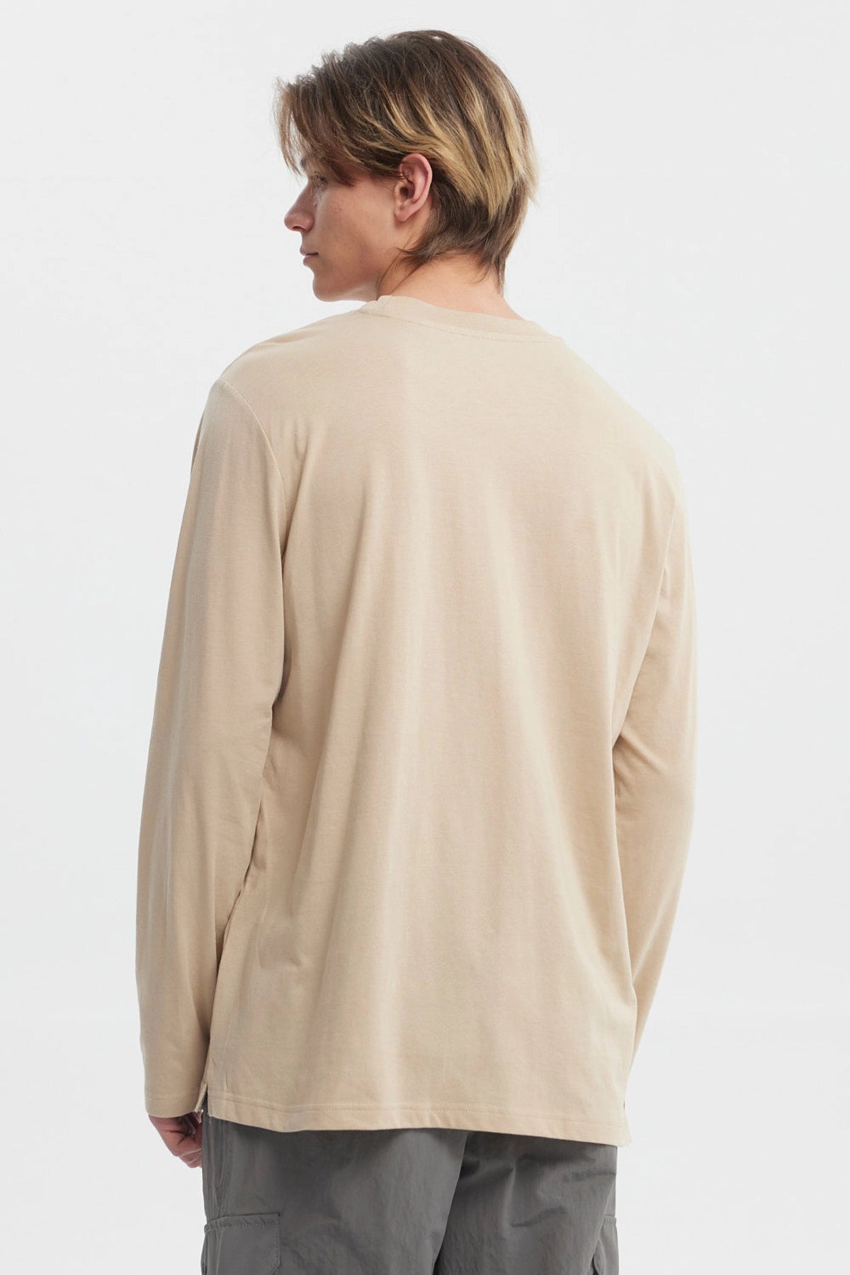 Polera beige oscuro hombre con brújula grande central y texto en el frente estilo casual relajado sin estampa trasera