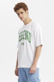 Polera oversize blanca para hombre con la palabra Legend y el número 1760 en verde al frente estilo universitario