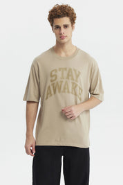 Polera oversize beige oscuro con texto Stay Awake en el pecho estilo casual relajado