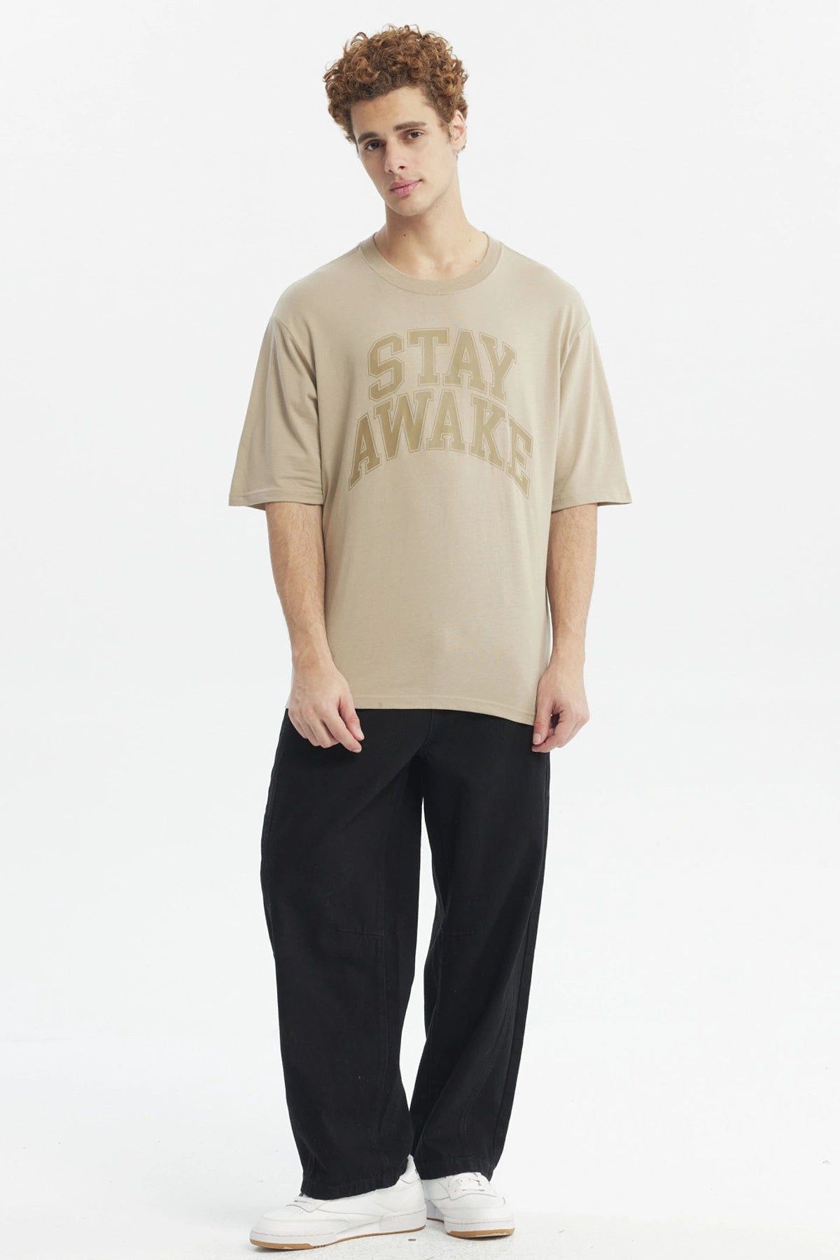 Polera oversize beige oscuro con texto Stay Awake en el pecho estilo casual relajado