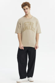 Polera oversize beige oscuro con texto Stay Awake en el pecho estilo casual relajado