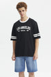 Polera negra hombre con texto Los Angeles Being Real al frente estilo urbano casual mangas con franjas blancas
