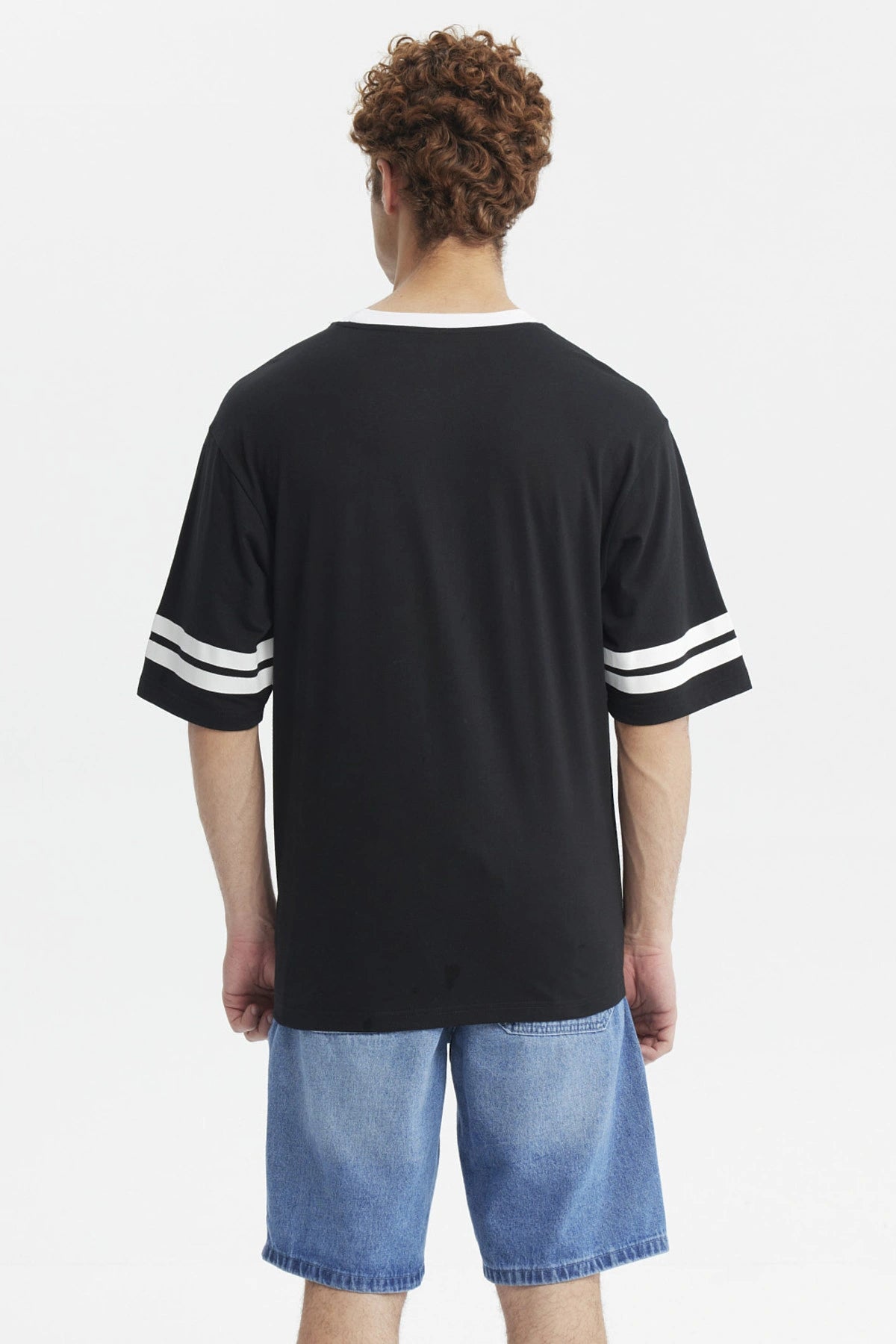 Polera negra hombre con texto Los Angeles Being Real al frente estilo urbano casual mangas con franjas blancas