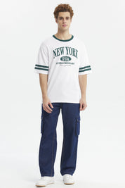 Polera blanca para hombre con texto New York USA Extraordinary en el pecho en verde y detalles de rayas en las mangas