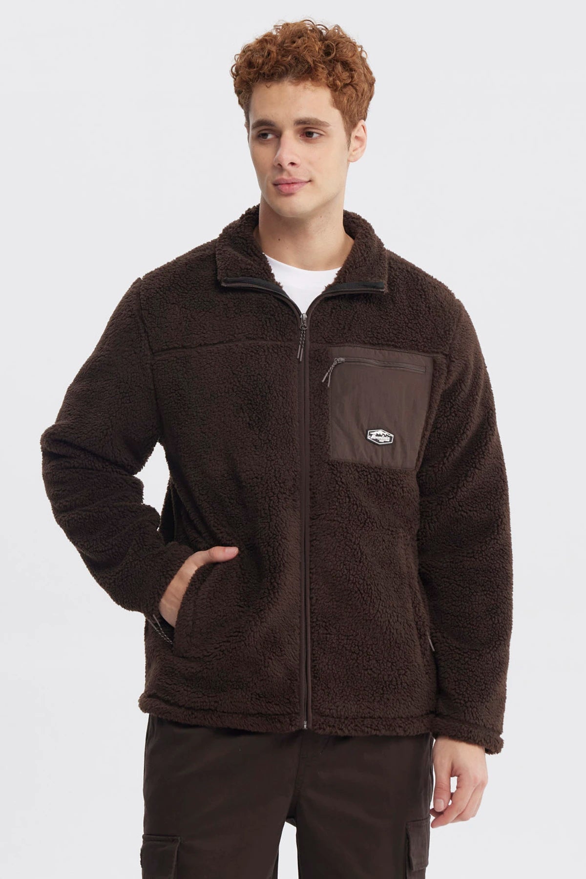 Polar juvenil slim chocolate con cierre frontal y bolsillo en el pecho con logo pequeño en fondo liso marrón oscuro