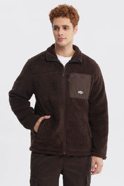 Polar juvenil slim chocolate con cierre frontal y bolsillo en el pecho con logo pequeño en fondo liso marrón oscuro