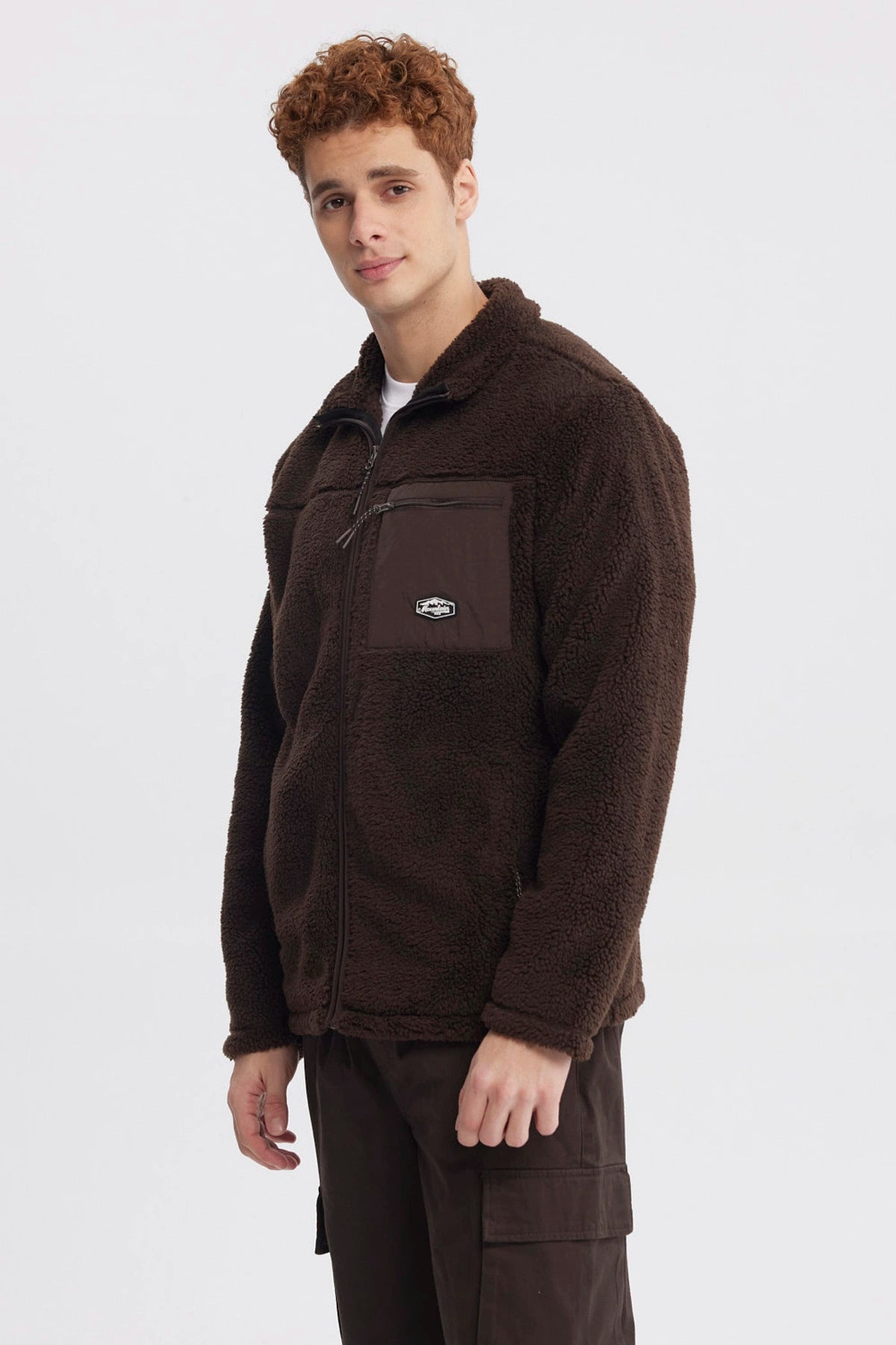 Polar juvenil slim chocolate con cierre frontal y bolsillo en el pecho con logo pequeño en fondo liso marrón oscuro