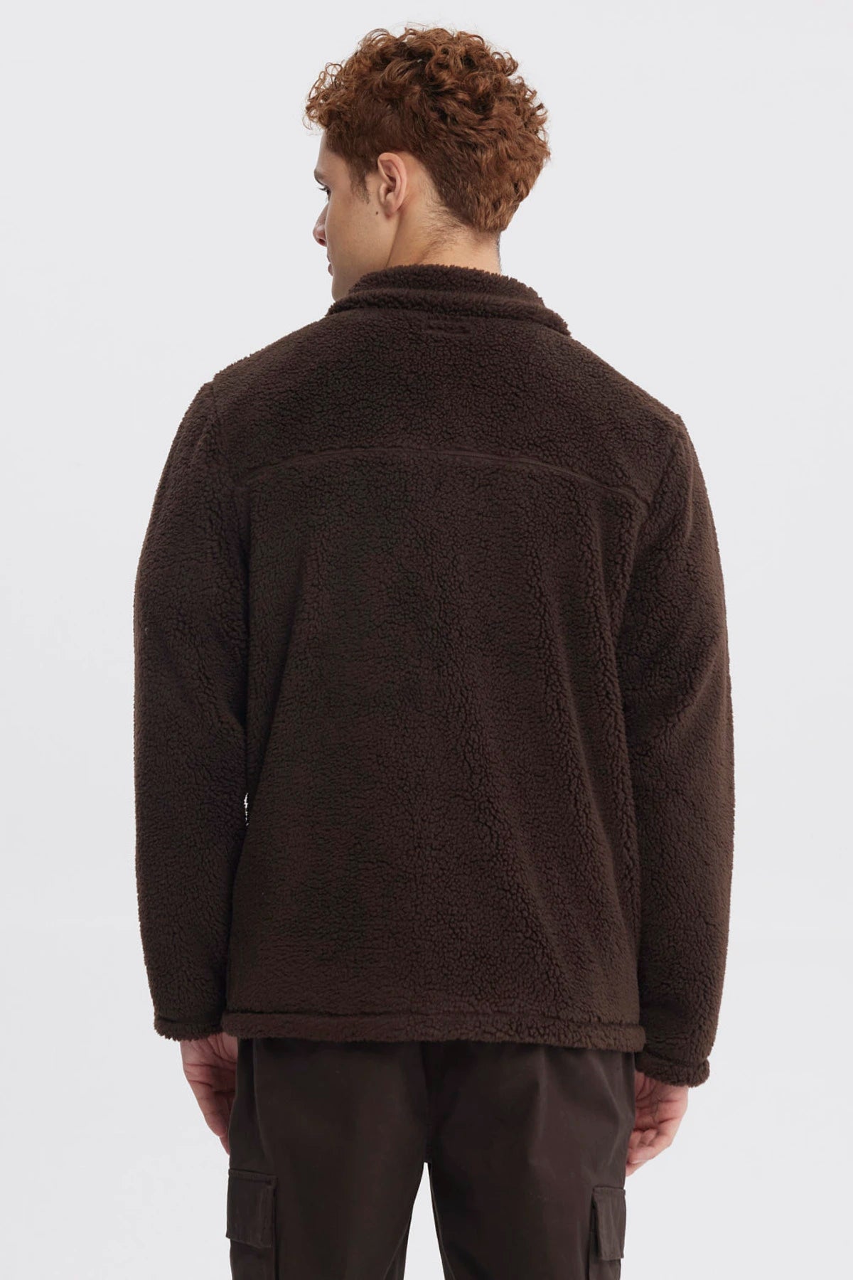 Polar juvenil slim chocolate con cierre frontal y bolsillo en el pecho con logo pequeño en fondo liso marrón oscuro