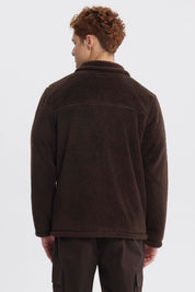 Polar juvenil slim chocolate con cierre frontal y bolsillo en el pecho con logo pequeño en fondo liso marrón oscuro