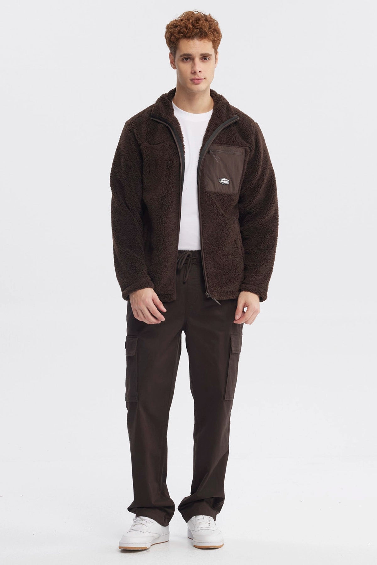 Polar juvenil slim chocolate con cierre frontal y bolsillo en el pecho con logo pequeño en fondo liso marrón oscuro