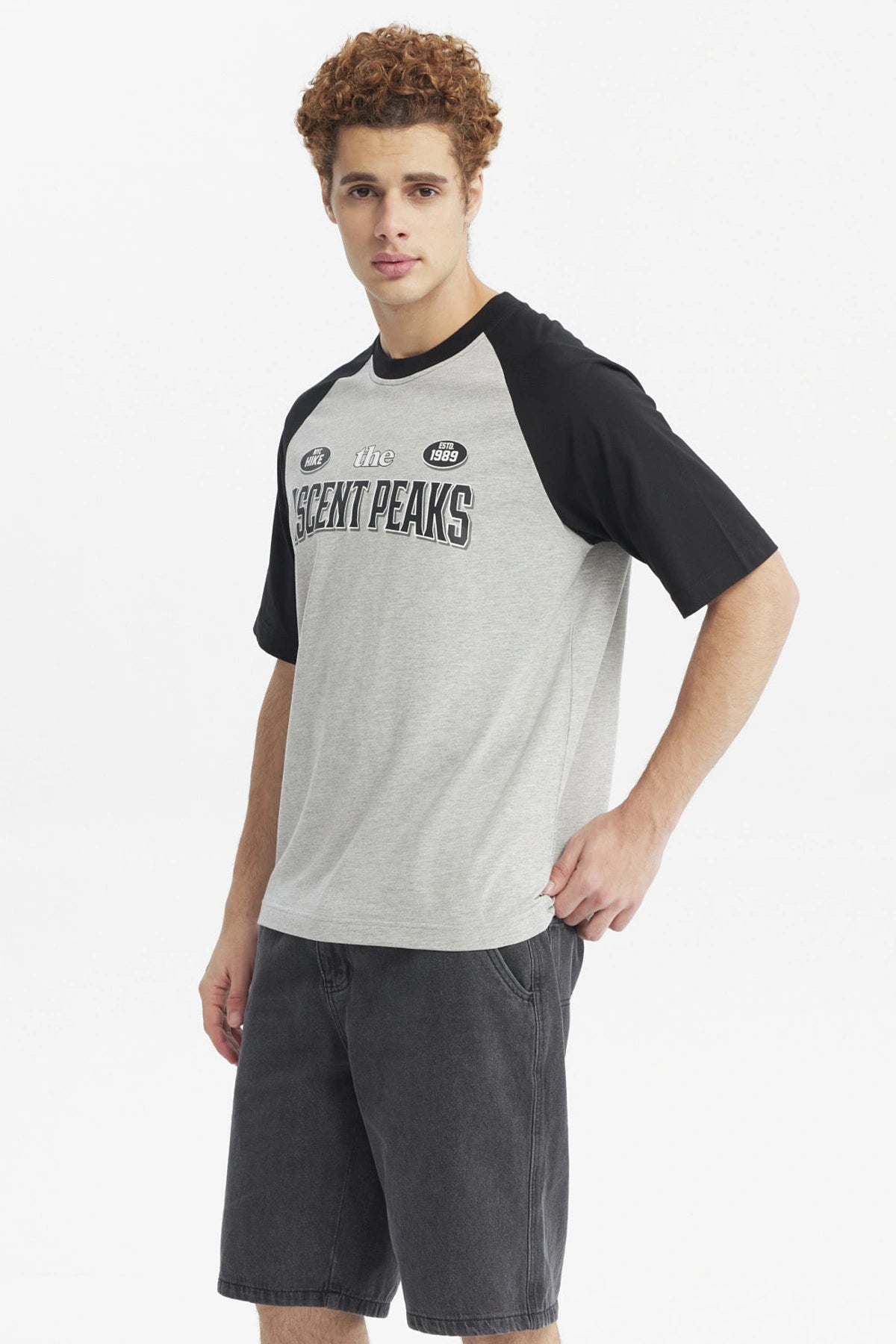 Polera hombre slim gris melange con mangas negras y estampa grande central Ascent Peaks con texto adicional Hike y Est 1989