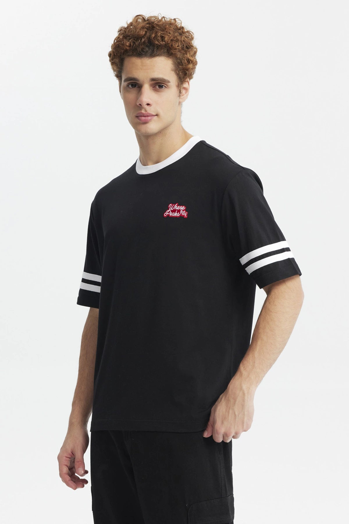 Polera oversize negra de hombre con detalles blancos en cuello y mangas estampa pequeña roja en el pecho lado izquierdo