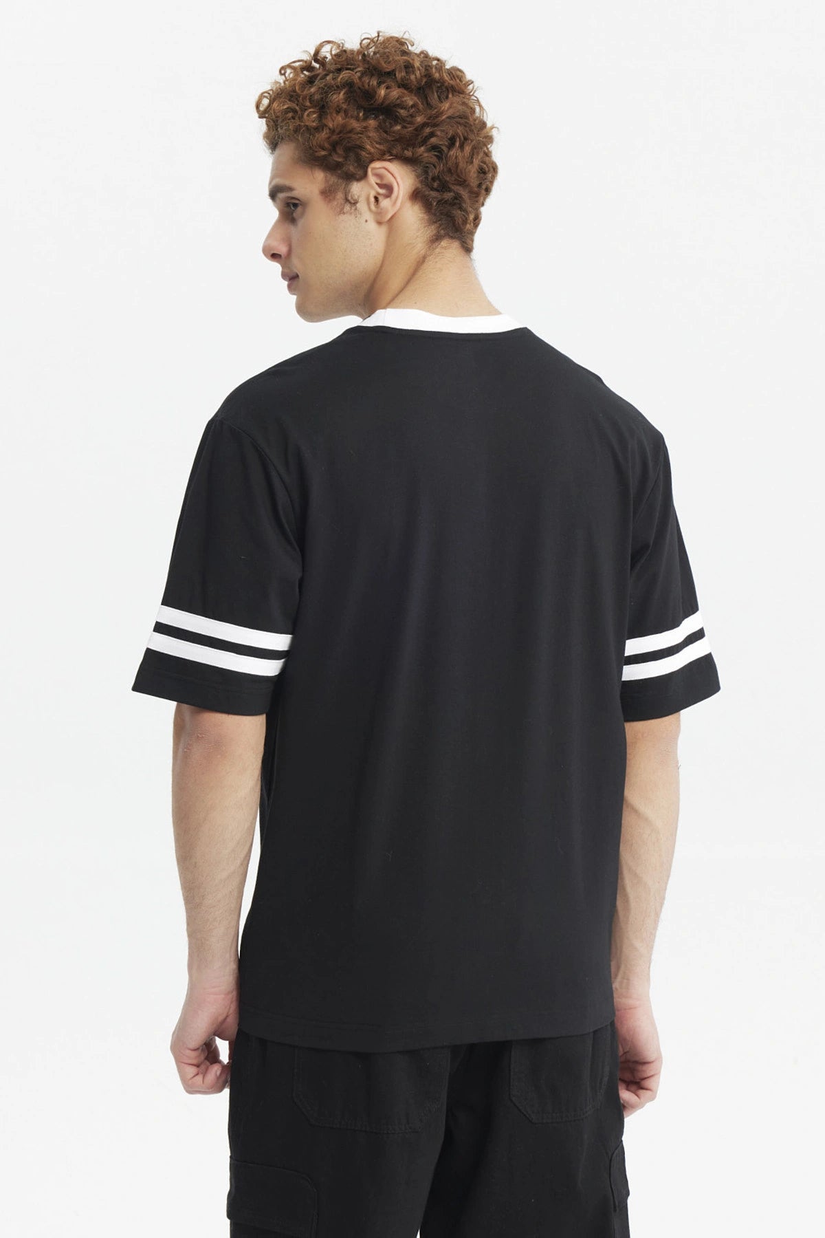 Polera oversize negra de hombre con detalles blancos en cuello y mangas estampa pequeña roja en el pecho lado izquierdo
