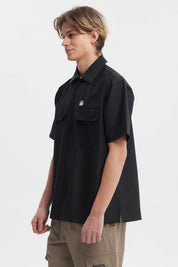 Camisa negra de hombre con doble bolsillo al frente y detalle de logo pequeño en el pecho