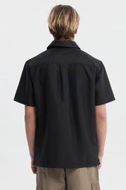 Camisa negra de hombre con doble bolsillo al frente y detalle de logo pequeño en el pecho