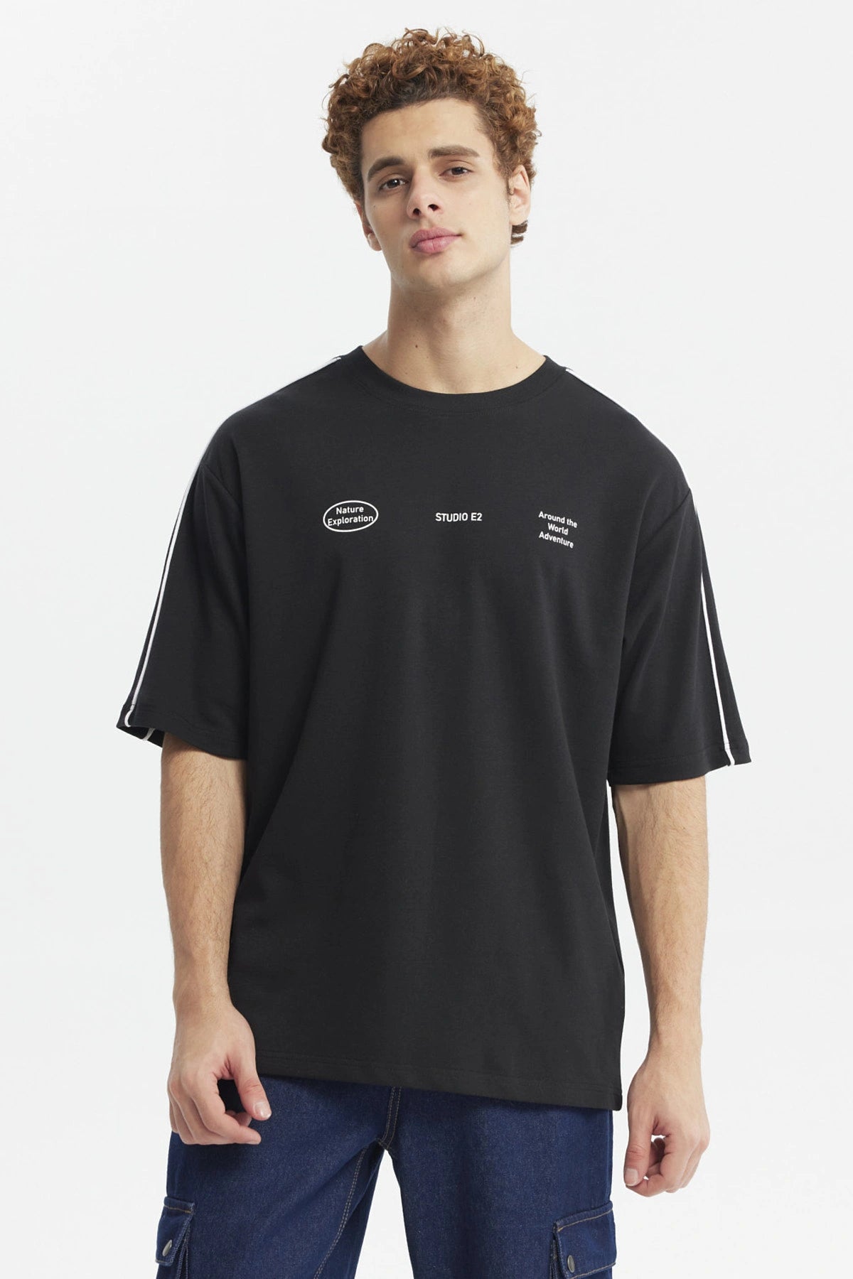 Polera negra oversize con doble línea blanca en mangas y estampado gráfico de texto pequeño en el pecho