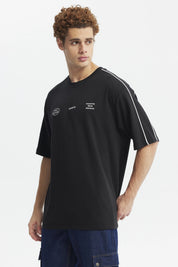 Polera negra oversize con doble línea blanca en mangas y estampado gráfico de texto pequeño en el pecho