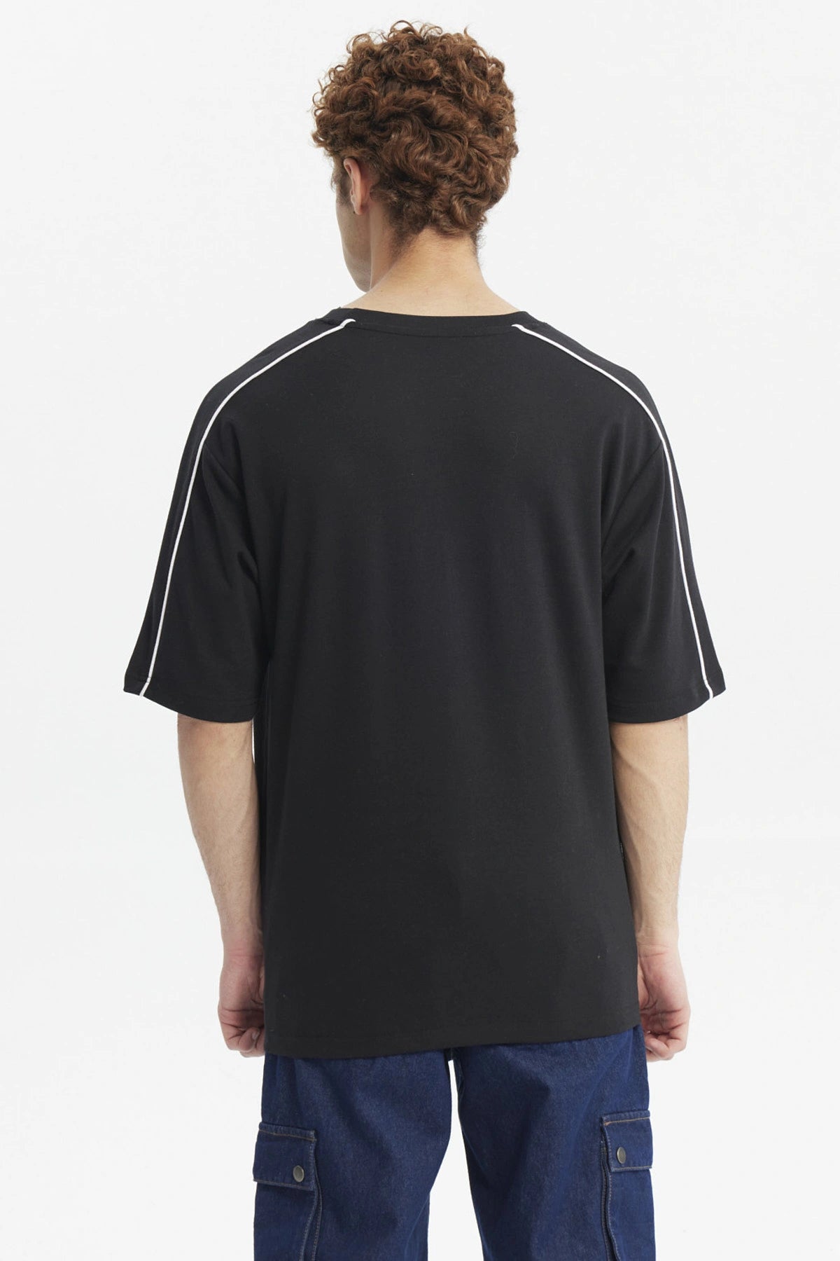 Polera negra oversize con doble línea blanca en mangas y estampado gráfico de texto pequeño en el pecho
