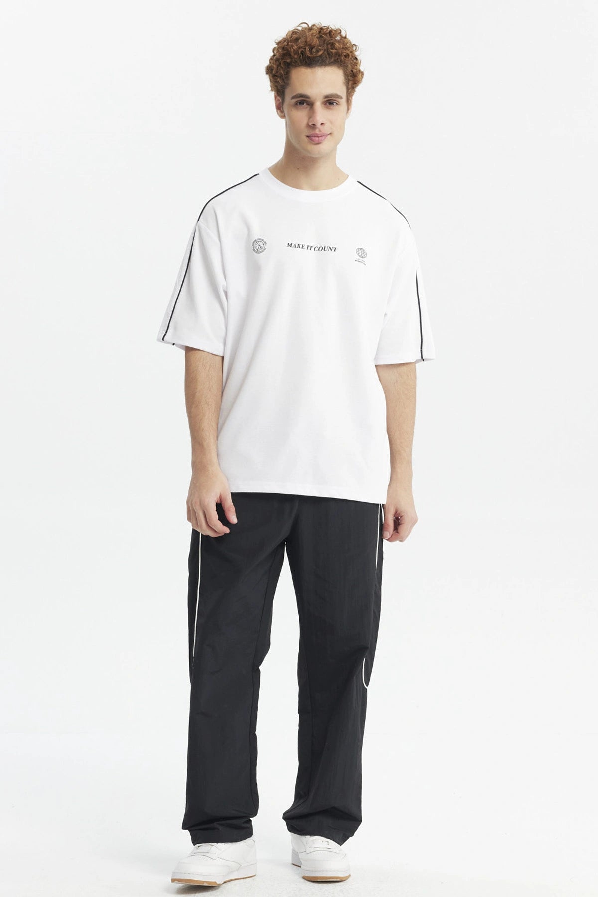 Polera oversize blanca con líneas negras en los hombros y texto Make It Count en el pecho diseño minimalista