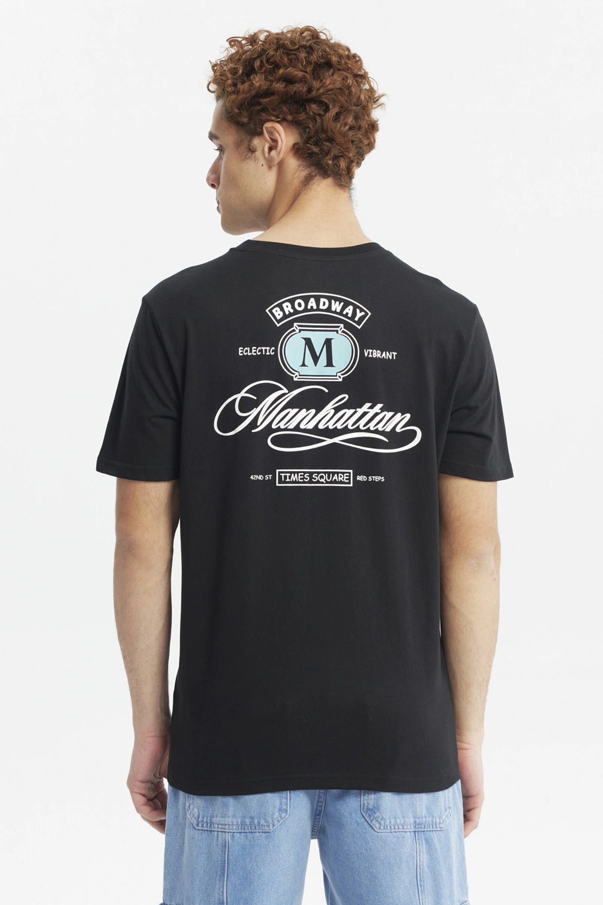 Polera negra para hombre de corte slim con estampado pequeño en el pecho que dice Manhattan en estilo cursivo elegante
