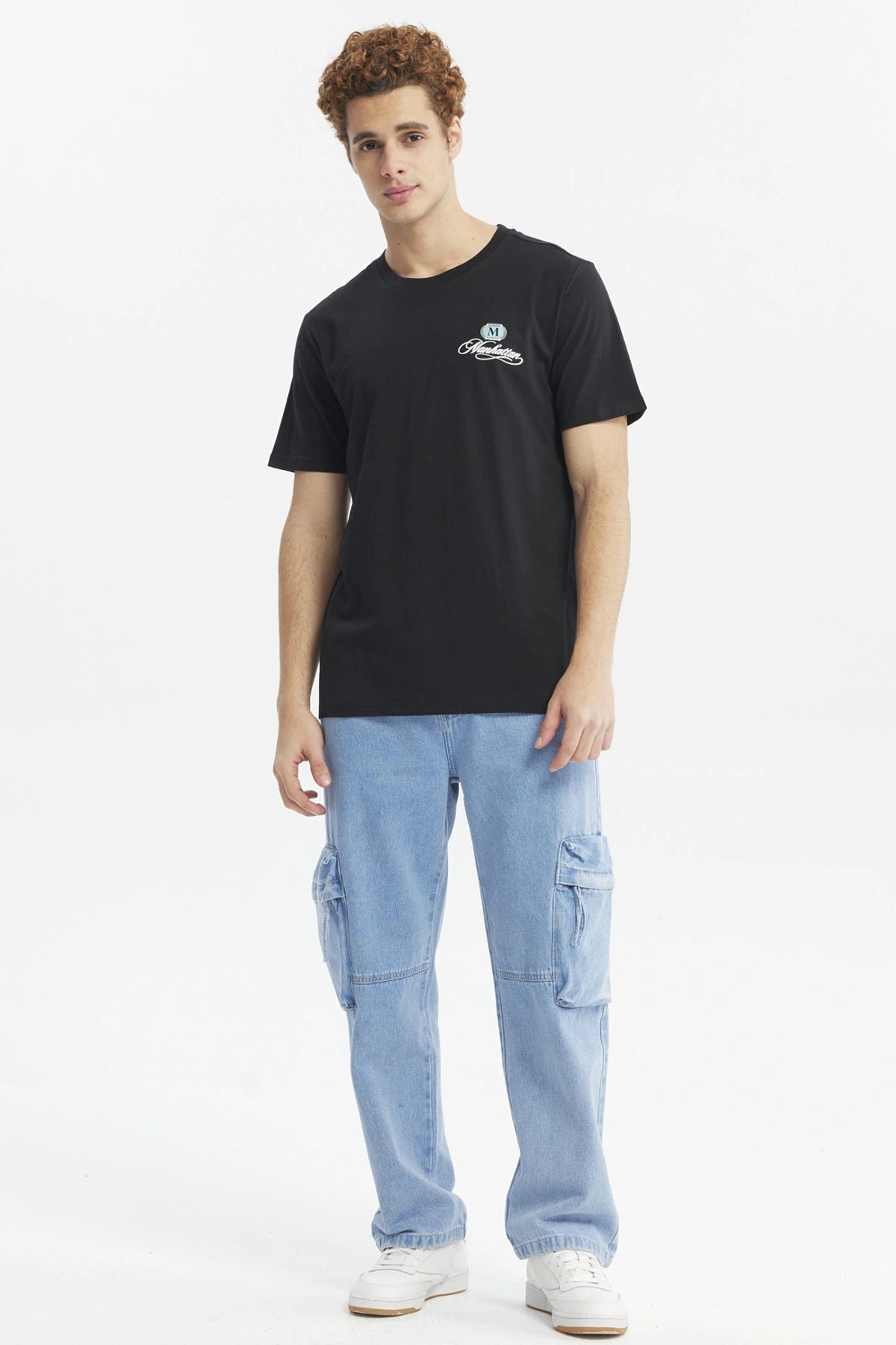 Polera negra para hombre de corte slim con estampado pequeño en el pecho que dice Manhattan en estilo cursivo elegante