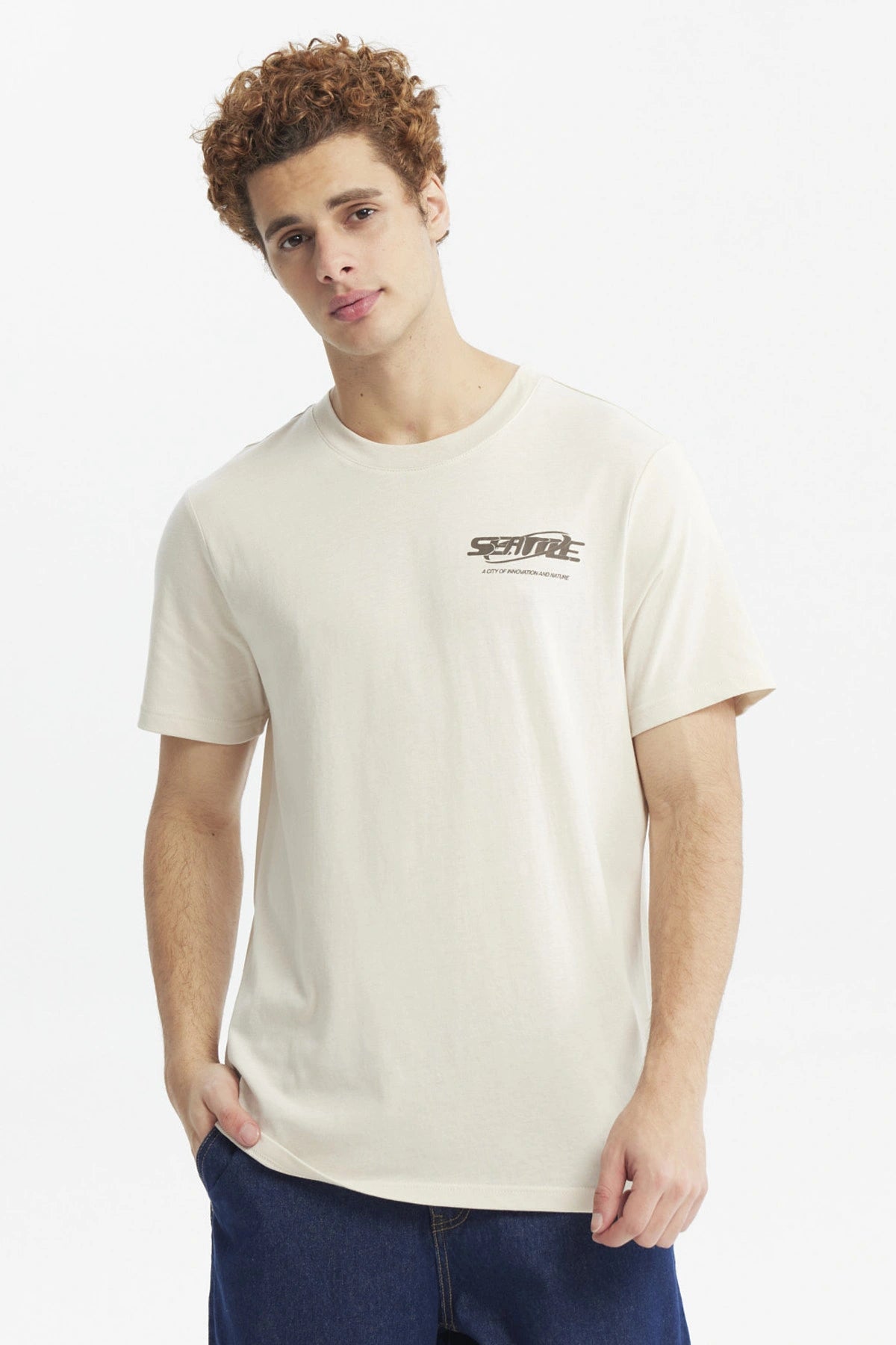 Polera slim beige hombre con texto Seattle en el pecho diseño urbano minimalista y fondo liso