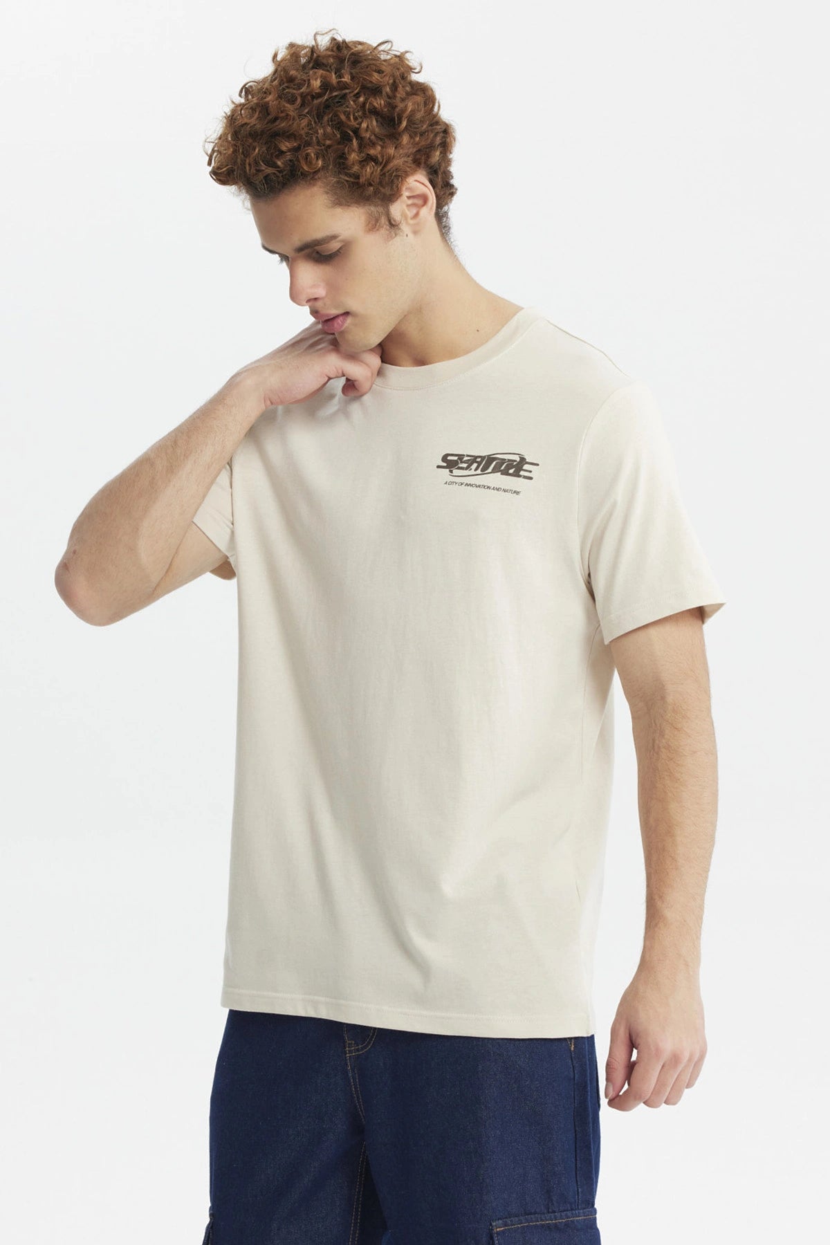Polera slim beige hombre con texto Seattle en el pecho diseño urbano minimalista y fondo liso