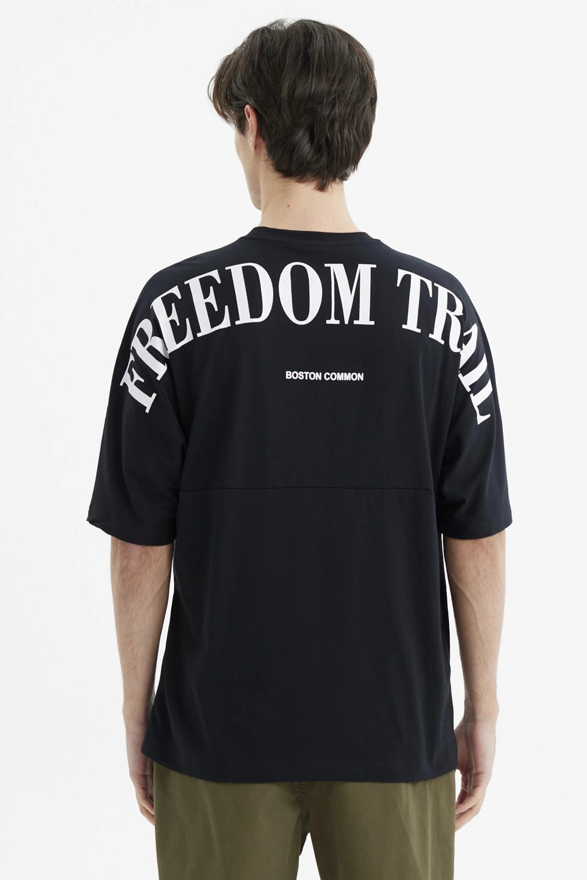 Polera negra slim para hombre con texto Freedom Trail en el pecho estilo minimalista casual y fondo blanco liso