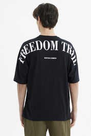 Polera negra slim para hombre con texto Freedom Trail en el pecho estilo minimalista casual y fondo blanco liso