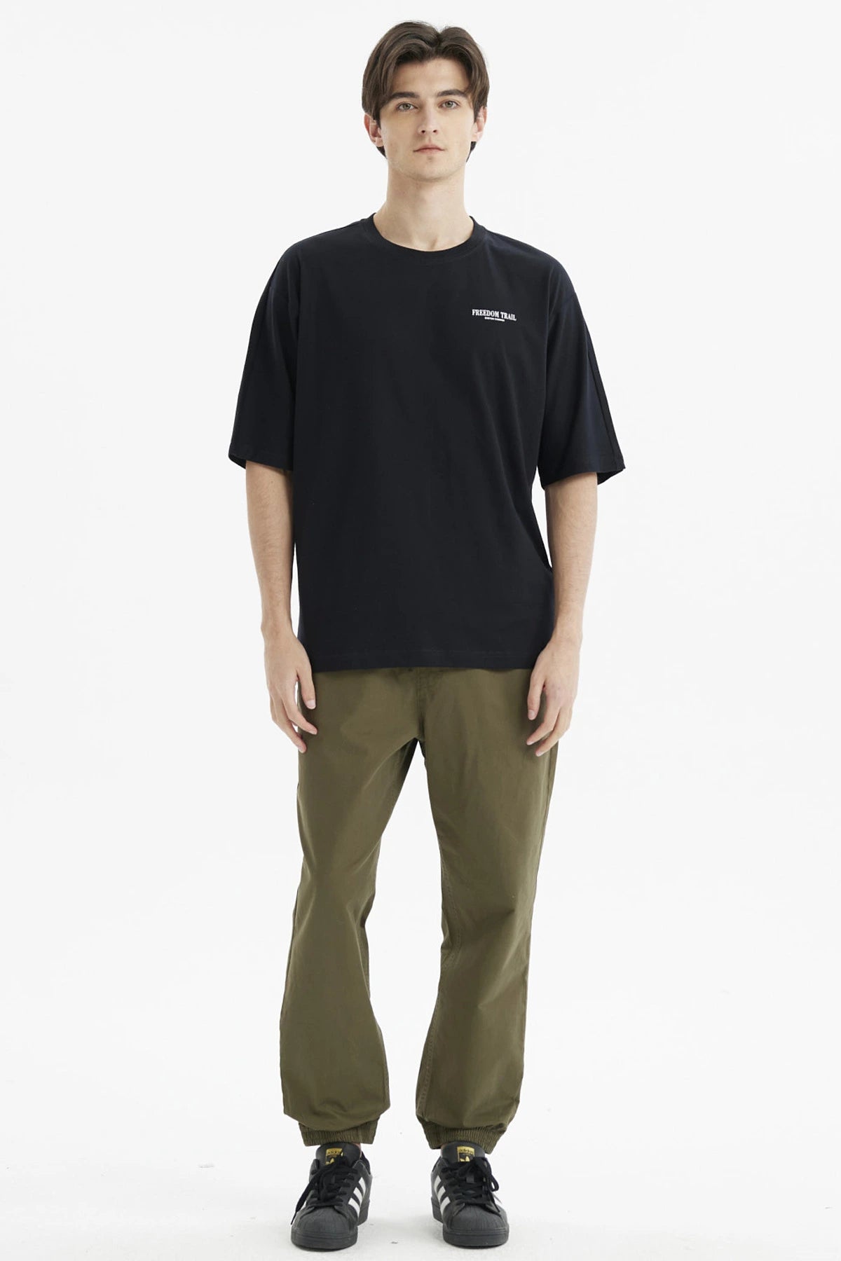 Polera negra slim para hombre con texto Freedom Trail en el pecho estilo minimalista casual y fondo blanco liso