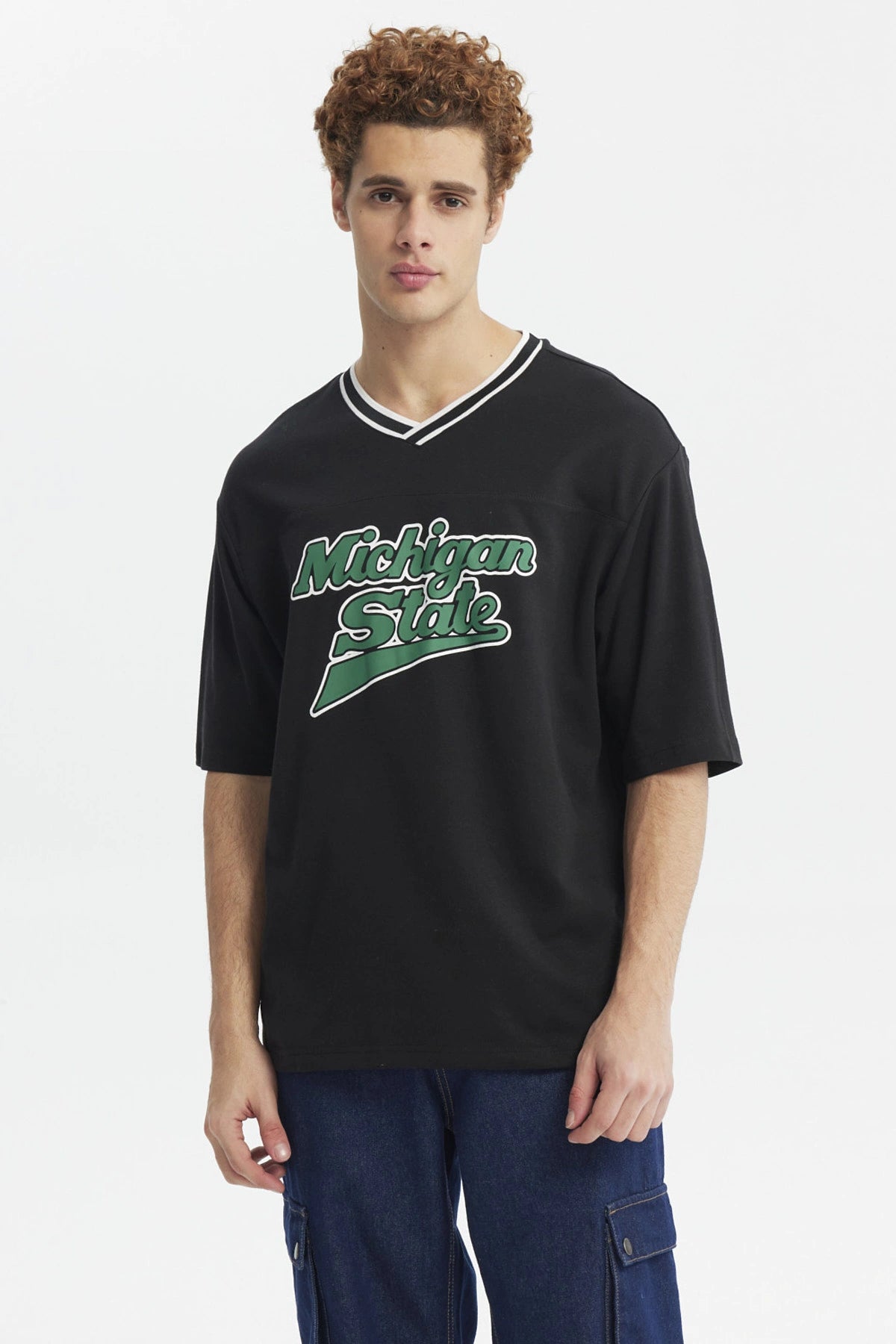 Polera negra slim para hombre con texto Michigan State en el pecho en verde y blanco estilo universitario