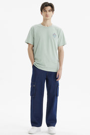Polera hombre verde claro con diseño de montañas en el pecho estilo minimalista y gráfico pequeño a la izquierda