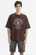 Polera oversize chocolate con estampado grande en el frente estilo universitario texto Escape the Ordinary