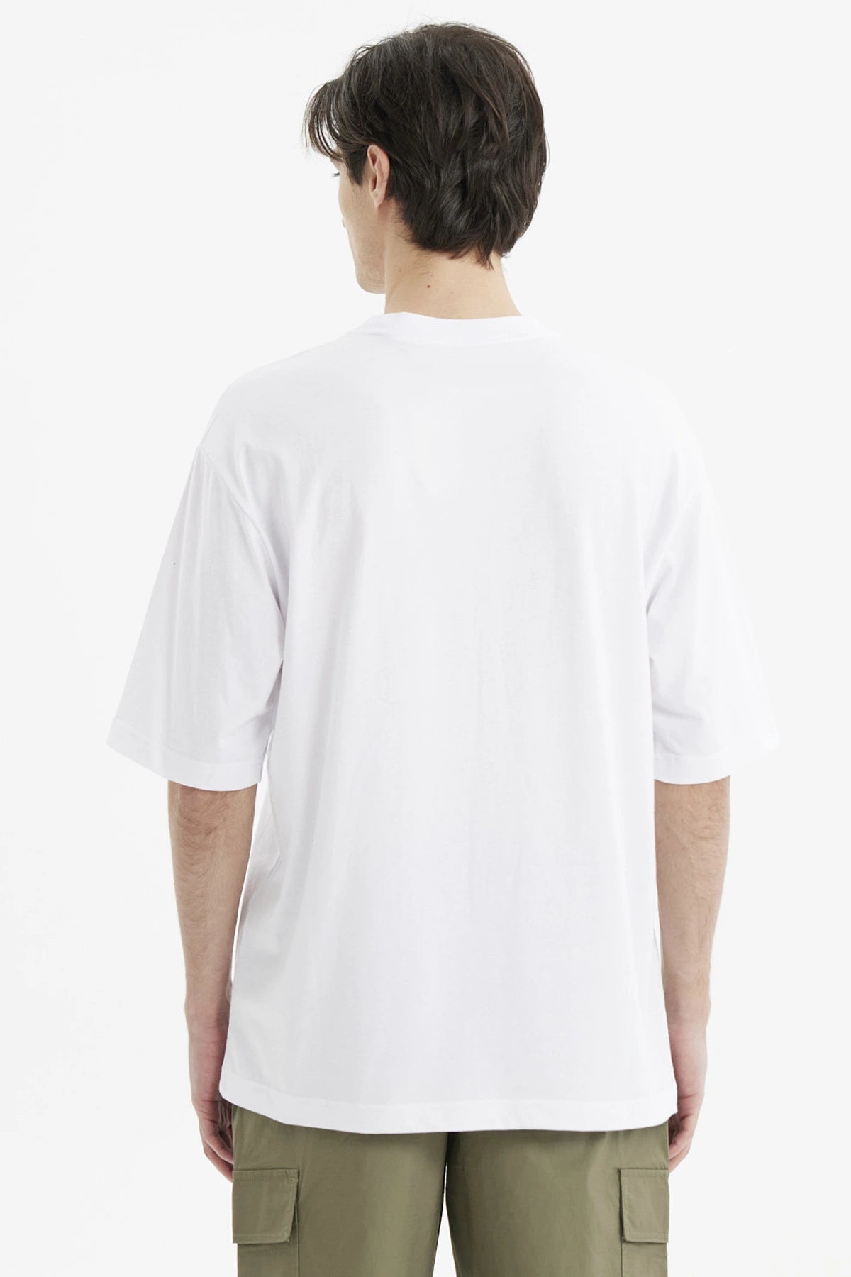 Polera oversize blanca para hombre con estampado grande central en negro que dice California y temática de eventos deportivos