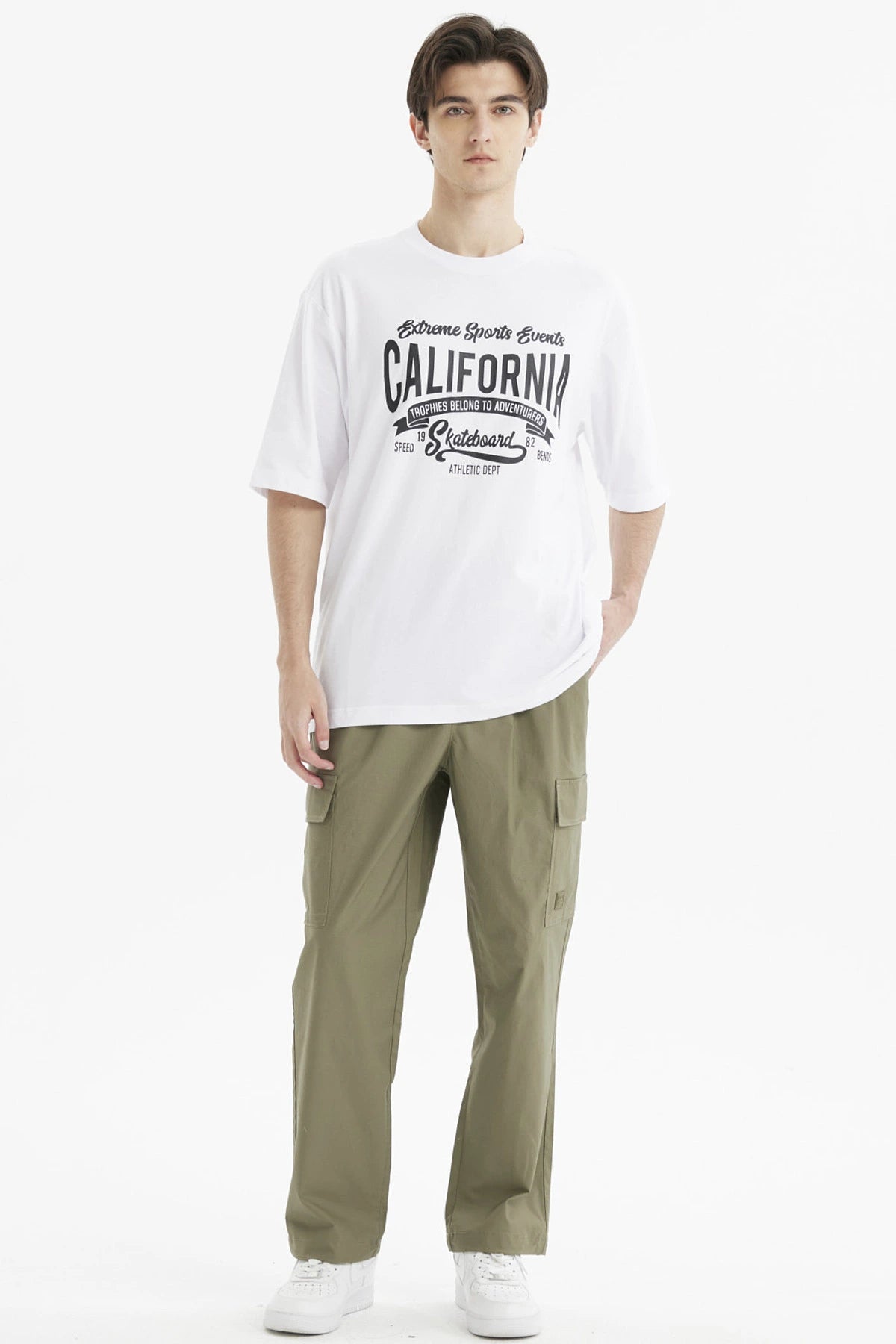 Polera oversize blanca para hombre con estampado grande central en negro que dice California y temática de eventos deportivos