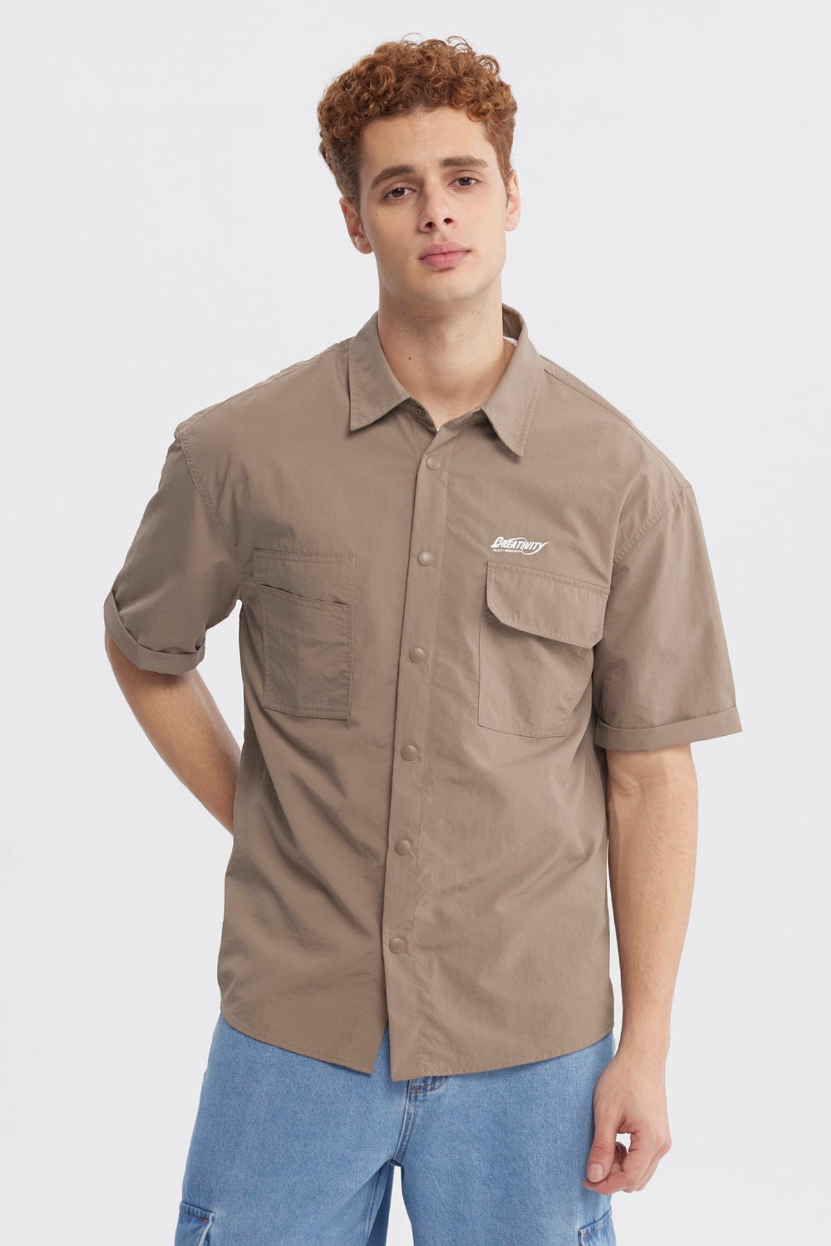 Camisa oversize café de hombre con doble bolsillo y texto pequeño en el pecho estilo casual y relajado