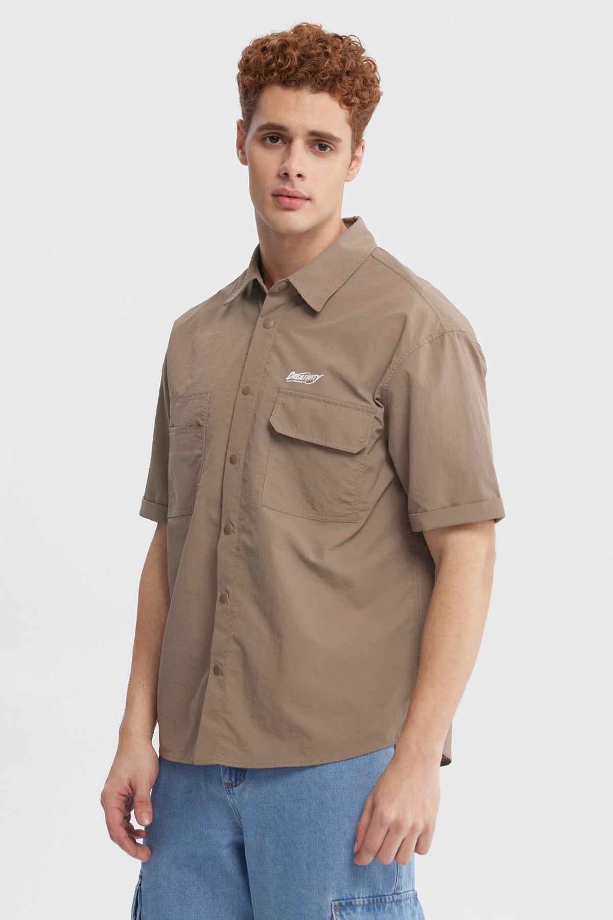 Camisa oversize café de hombre con doble bolsillo y texto pequeño en el pecho estilo casual y relajado