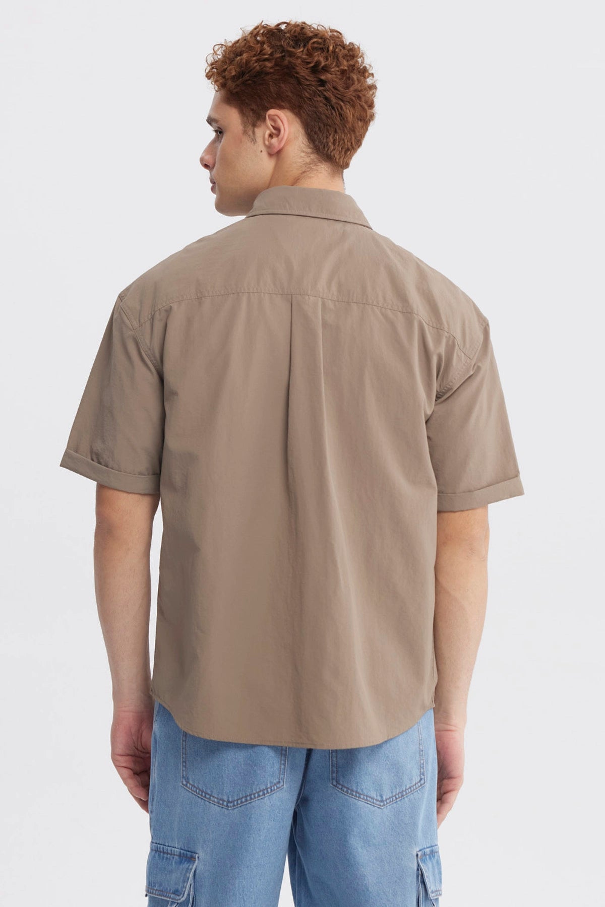 Camisa oversize café de hombre con doble bolsillo y texto pequeño en el pecho estilo casual y relajado
