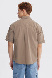 Camisa oversize café de hombre con doble bolsillo y texto pequeño en el pecho estilo casual y relajado