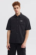 Camisa oversize negra de hombre con doble bolsillo y logo blanco en el pecho estilo casual sin estampa lisa